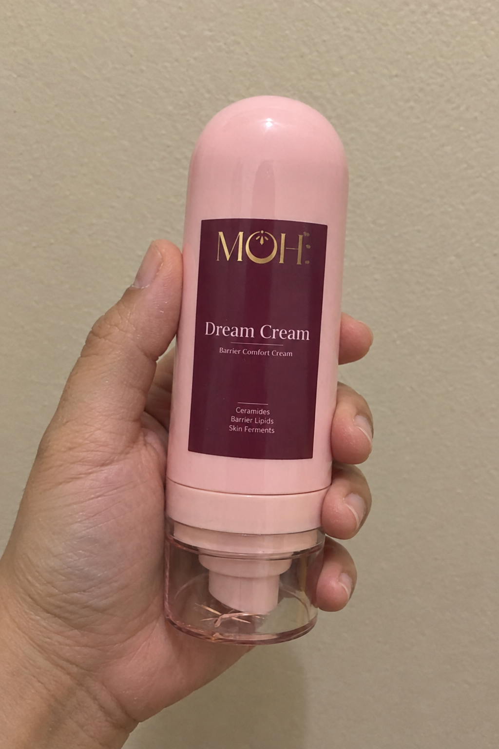 Dream Cream held against a beige wall